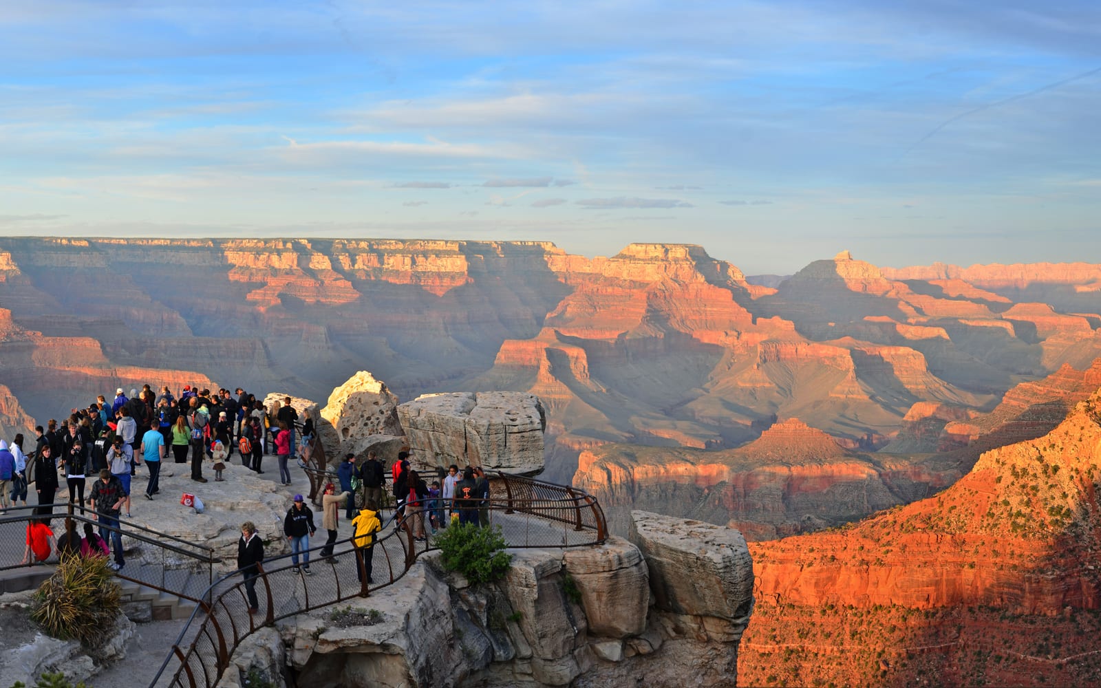 The canyon glows orange as people visit Mather Point, a rock outcropping that juts into Grand Canyon