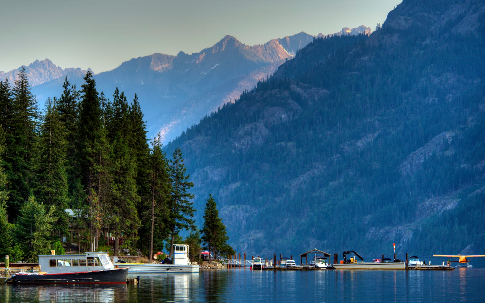boats on the water with mountains and trees surrounding