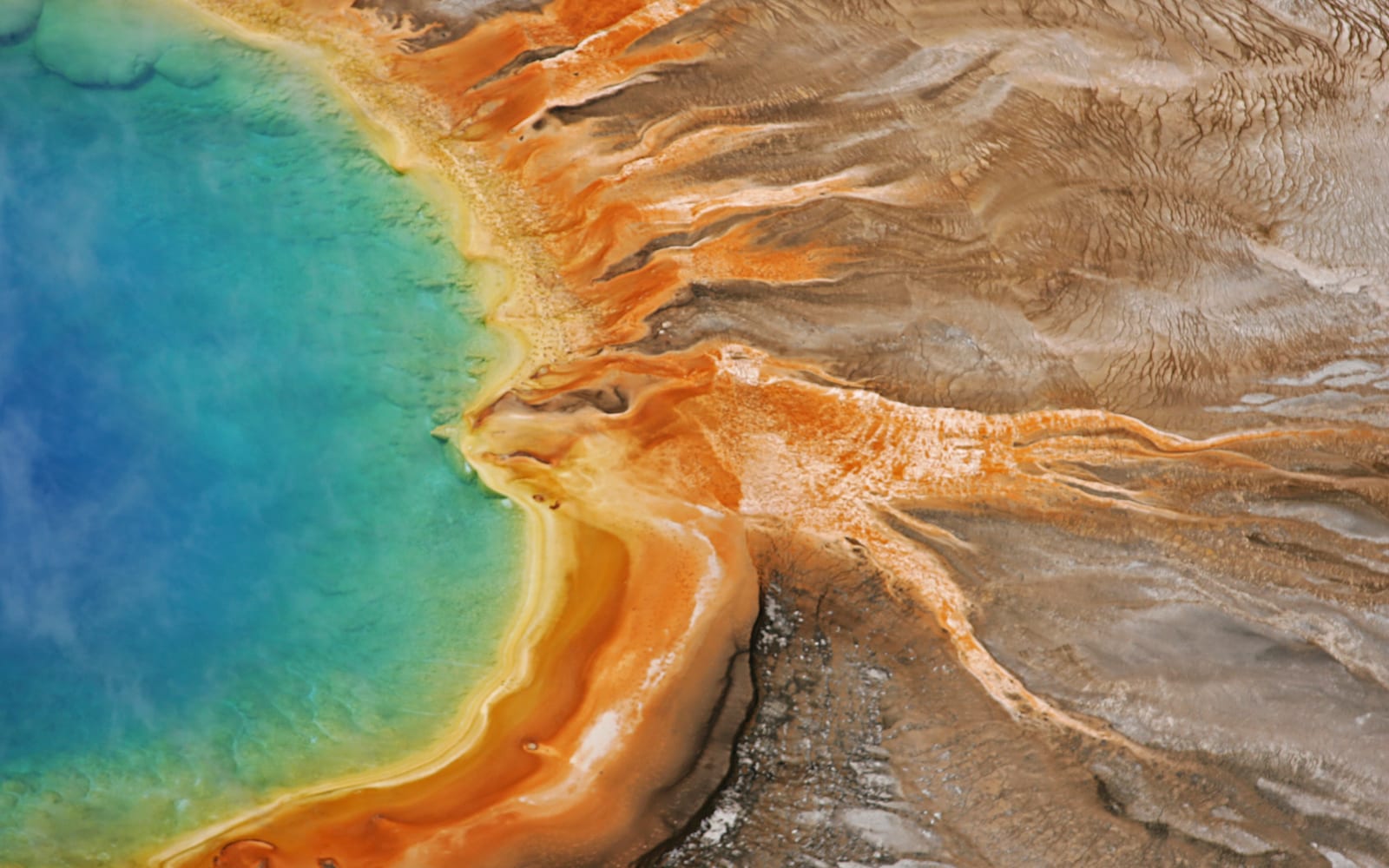 Brilliant blues and greens of a hot spring ringed by oranges, yellows, reds, and browns.